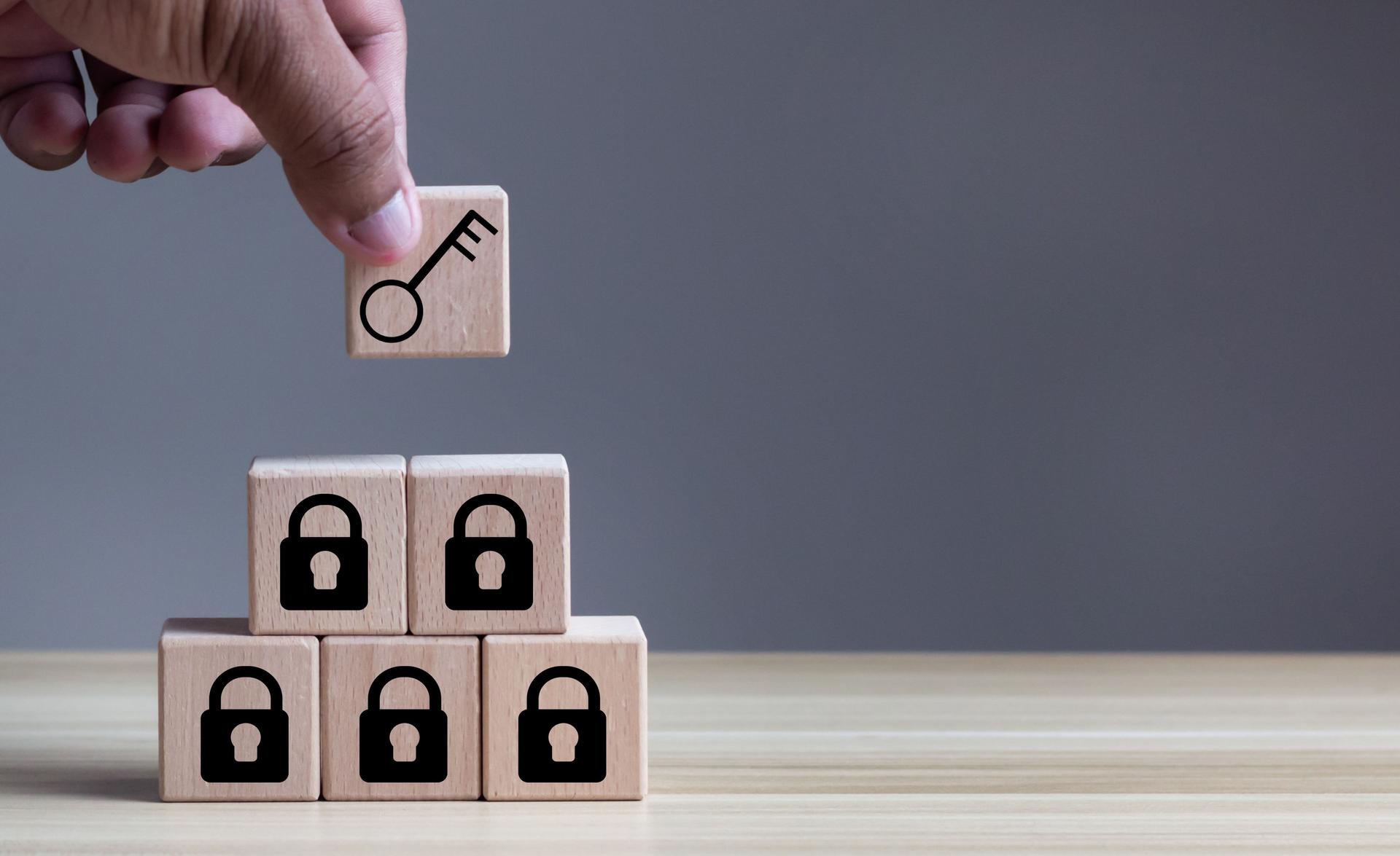Business planning and strategy concept for business development. Keys unlocking to achieve goals and mission. Man hold wood cubes with unlock key and keys icon on table; light background. Copy space.
